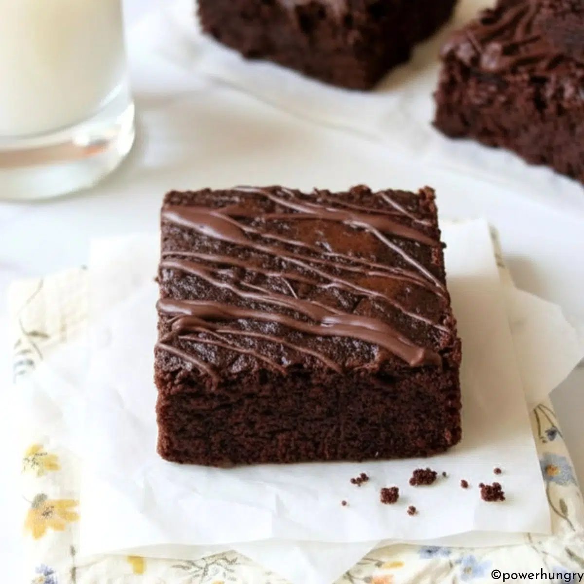 vegan carob almond flour brownie on a napkin with a glass of milk