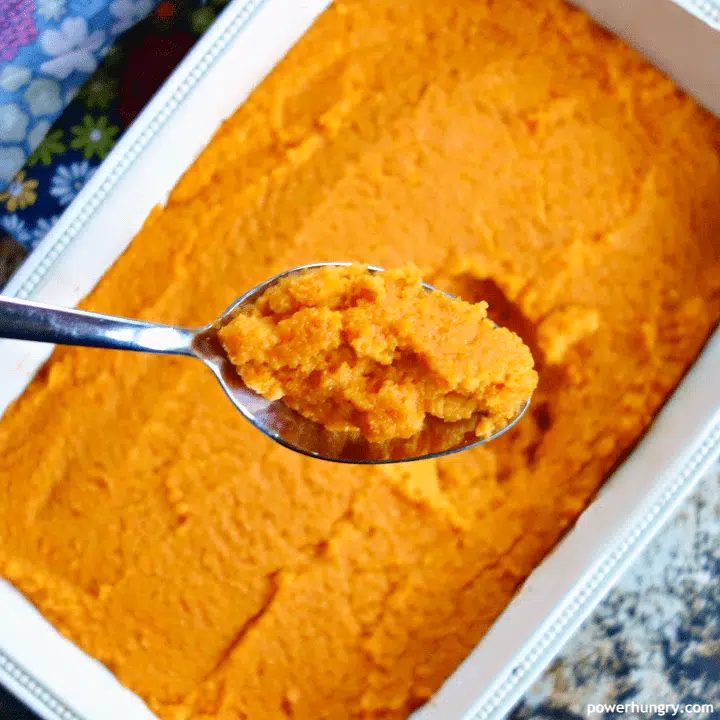 Vegan carrot soufflé in a cream-colored serving dish, with a closeup of a spoonful of the soufflé