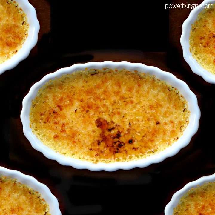 Vegan creme brulee in white scallopped dishes on a black background
