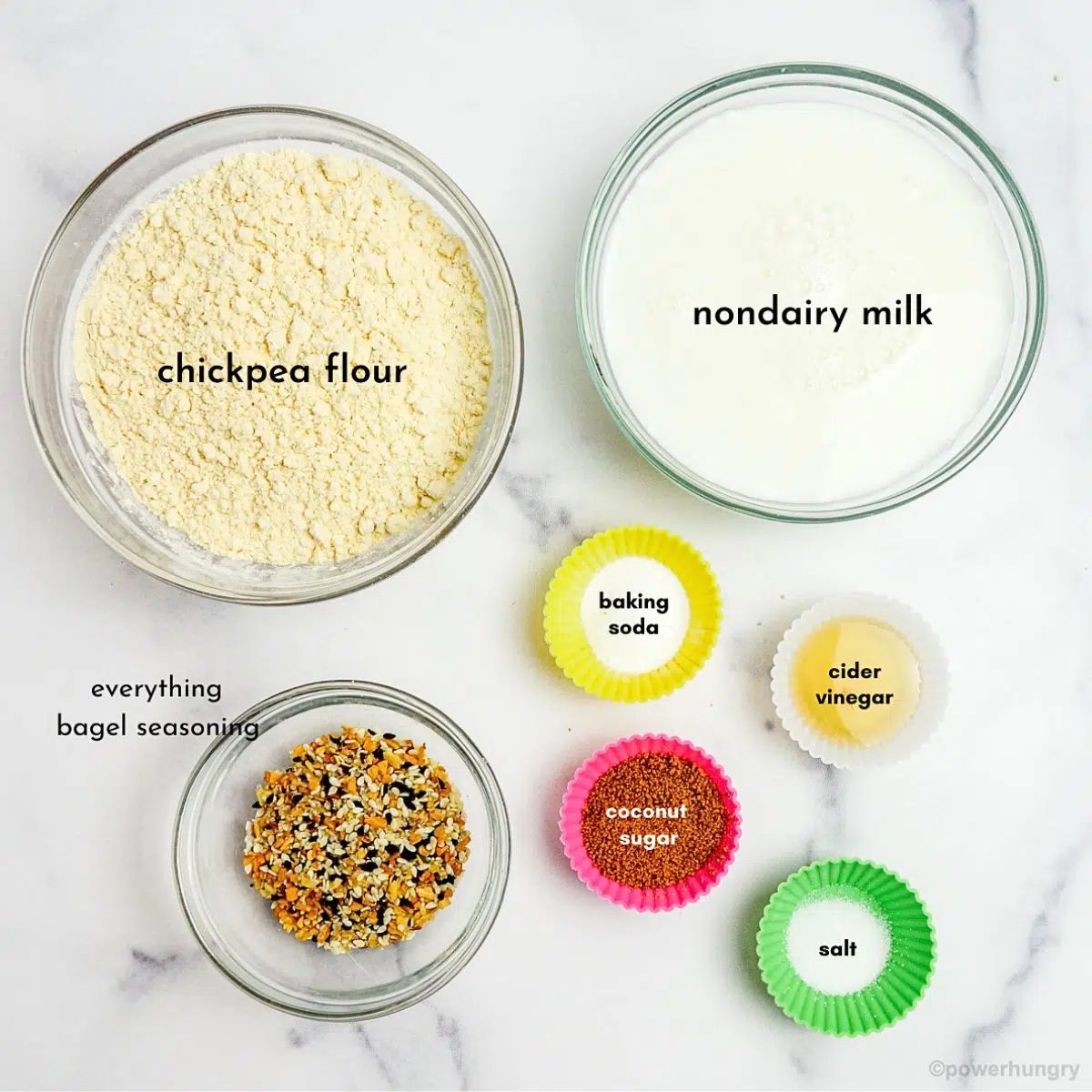 ingredients, in small prep bowls, on a white marble surface, ready to make chickpea flour bagels