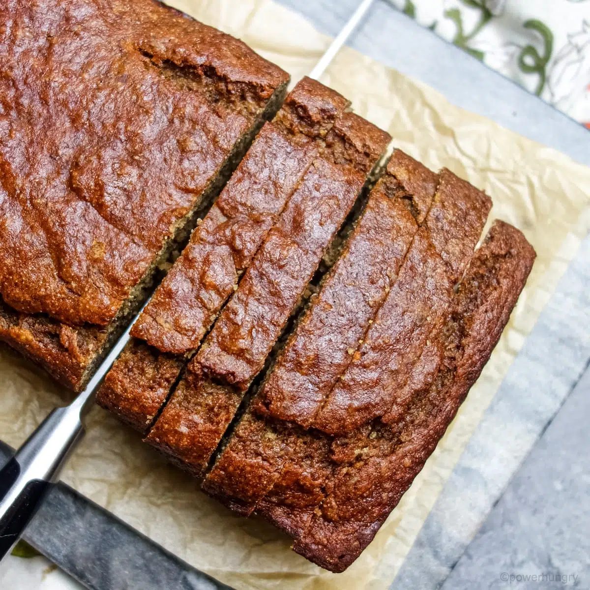 overhead shot of banana bread being sliced on a wood cutting board