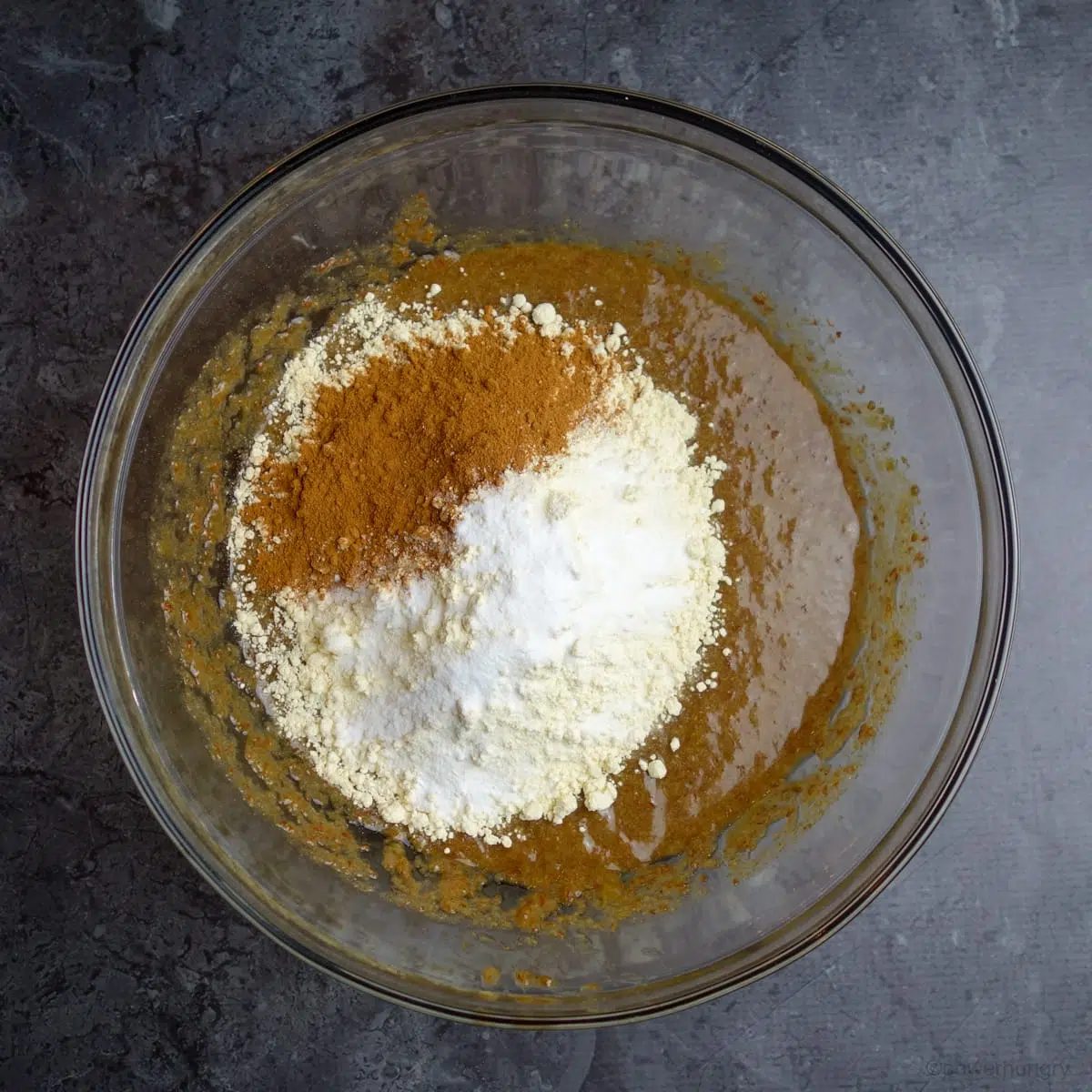 glass bowl with baking ingredients on a grey marble countertop