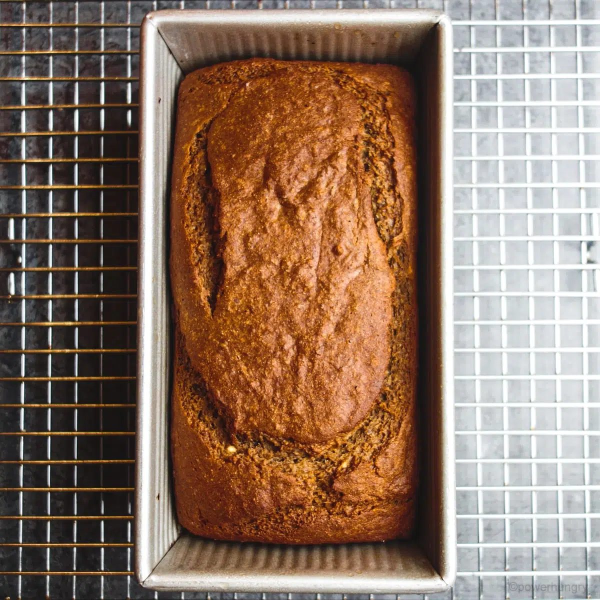 loaf of bread in metal loaf pan on a silver cooling rack