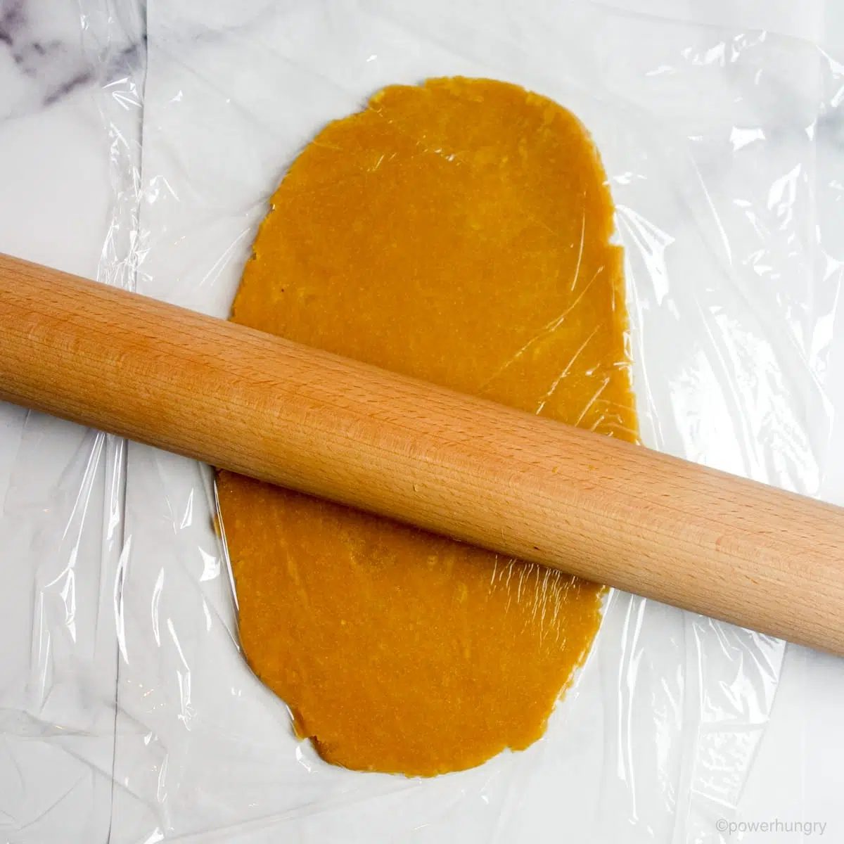 chickpea cookie dough being rolled out on a marble surface