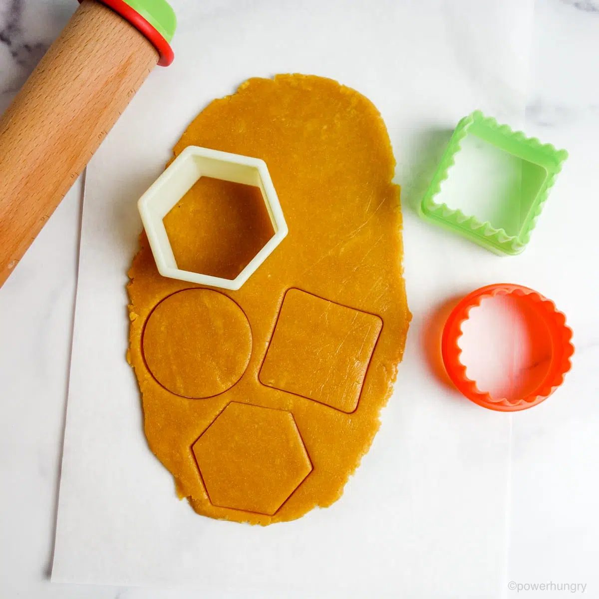 chickpea flour cookie dough being cut with cookie cutters
