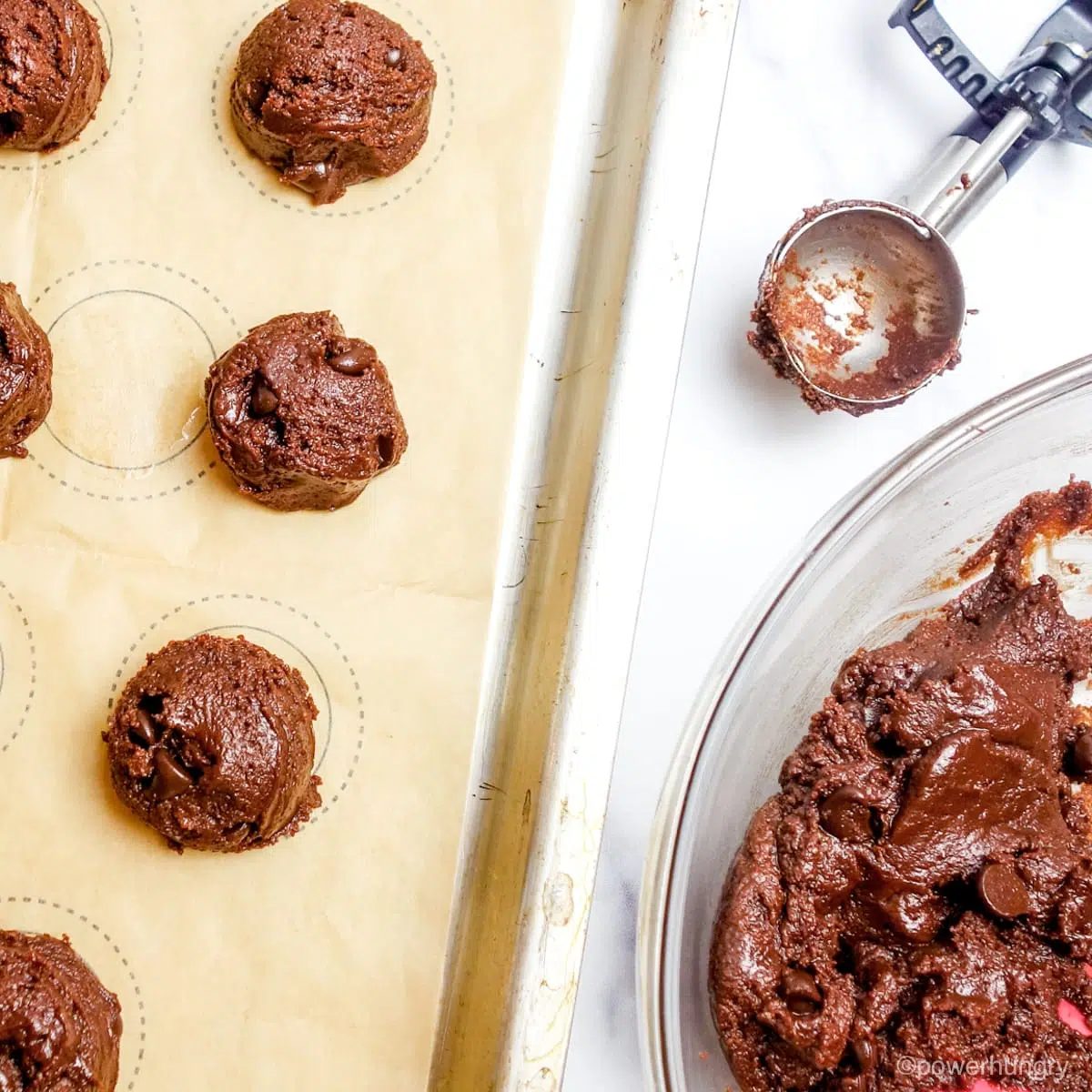 scooped chocolate avocado coconut flour cookie dough on a parchment lined baking sheet