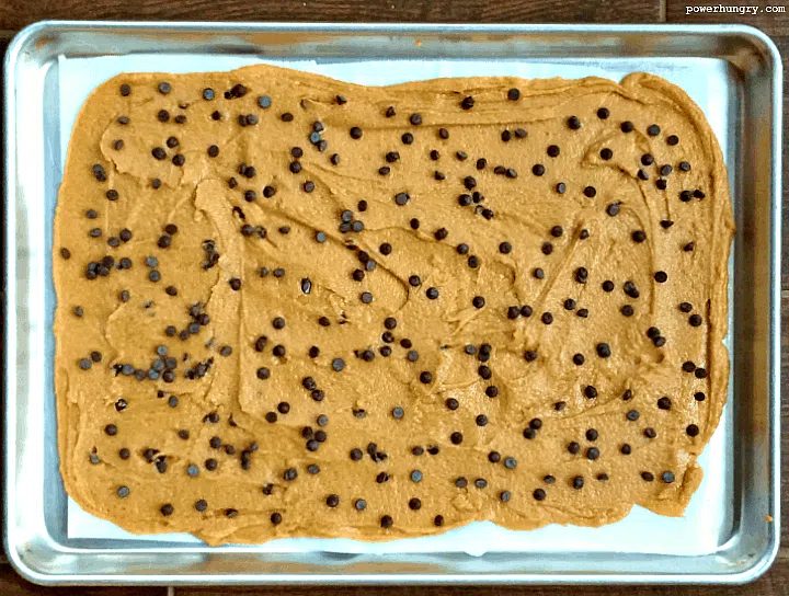 cookie brittle sough spread out on a baking sheet and sprinkled with chocolate chips