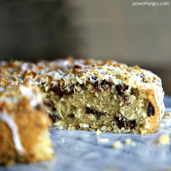 close up of coconut almond cake with icing , a piece cut out to reveal interior