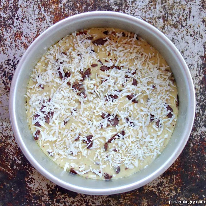 vegan coconut almond flour cake batter in a silver baking pan, with coconut sprinkled on top