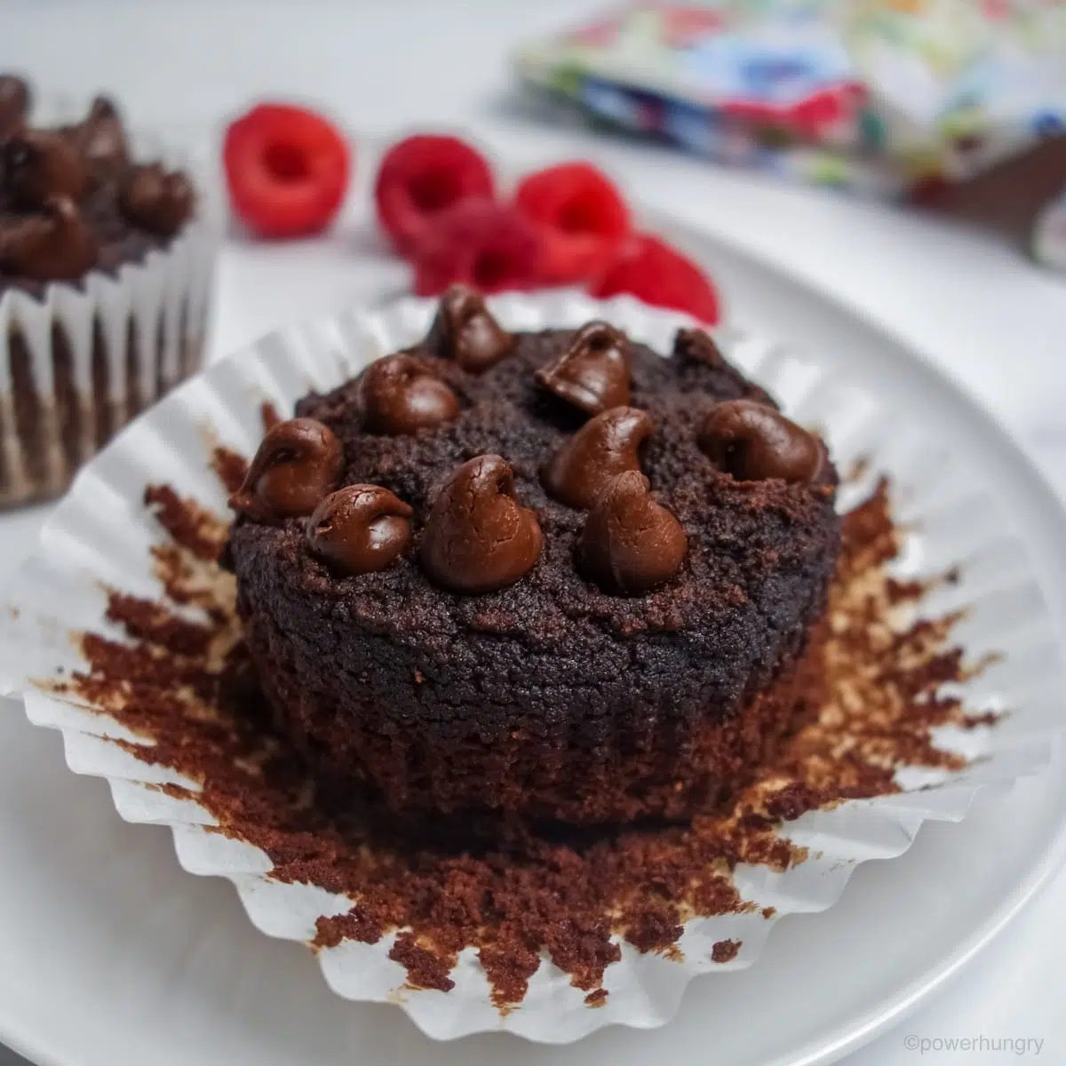a partially unwrapped vegan coconut flour chocolate cupcake on a white plate