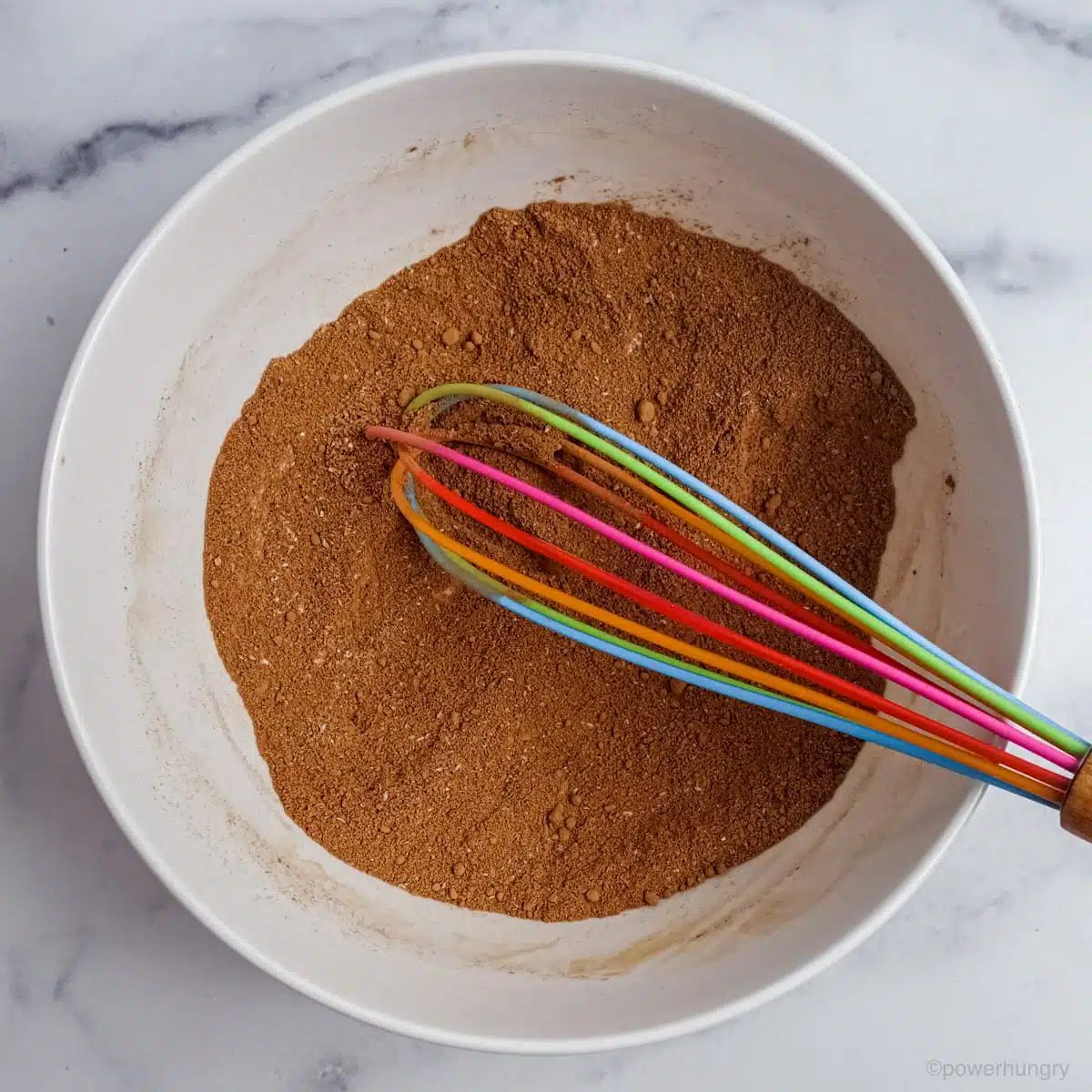 the dry ingredients for vegan coconut flour chocolate cupcakes in a white bowl