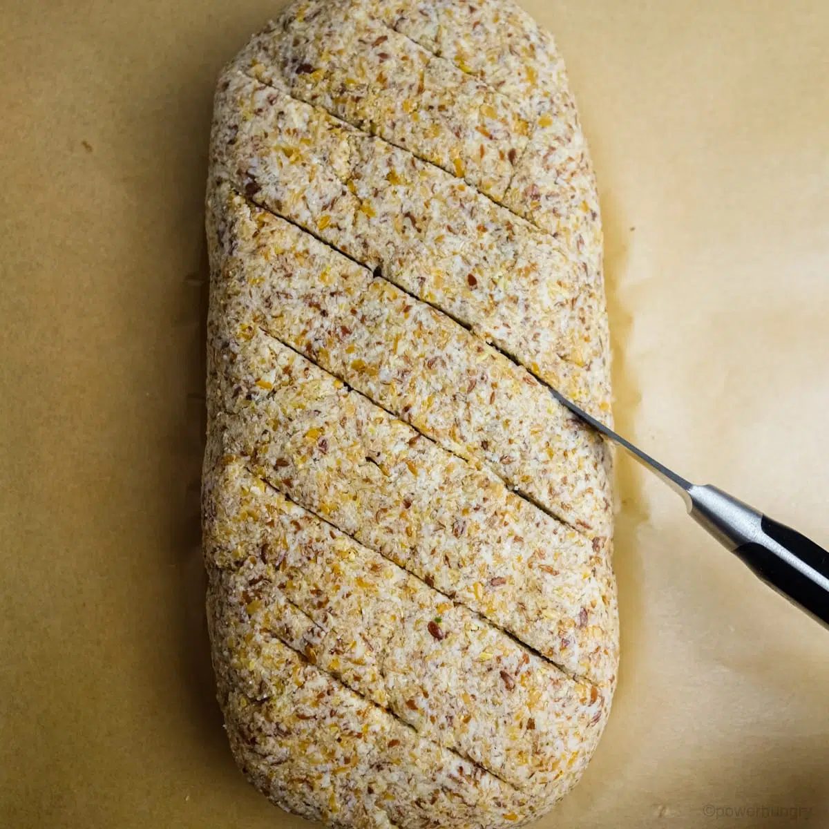 Unbaked coconut flour flax bread with several slashes being made with a knife