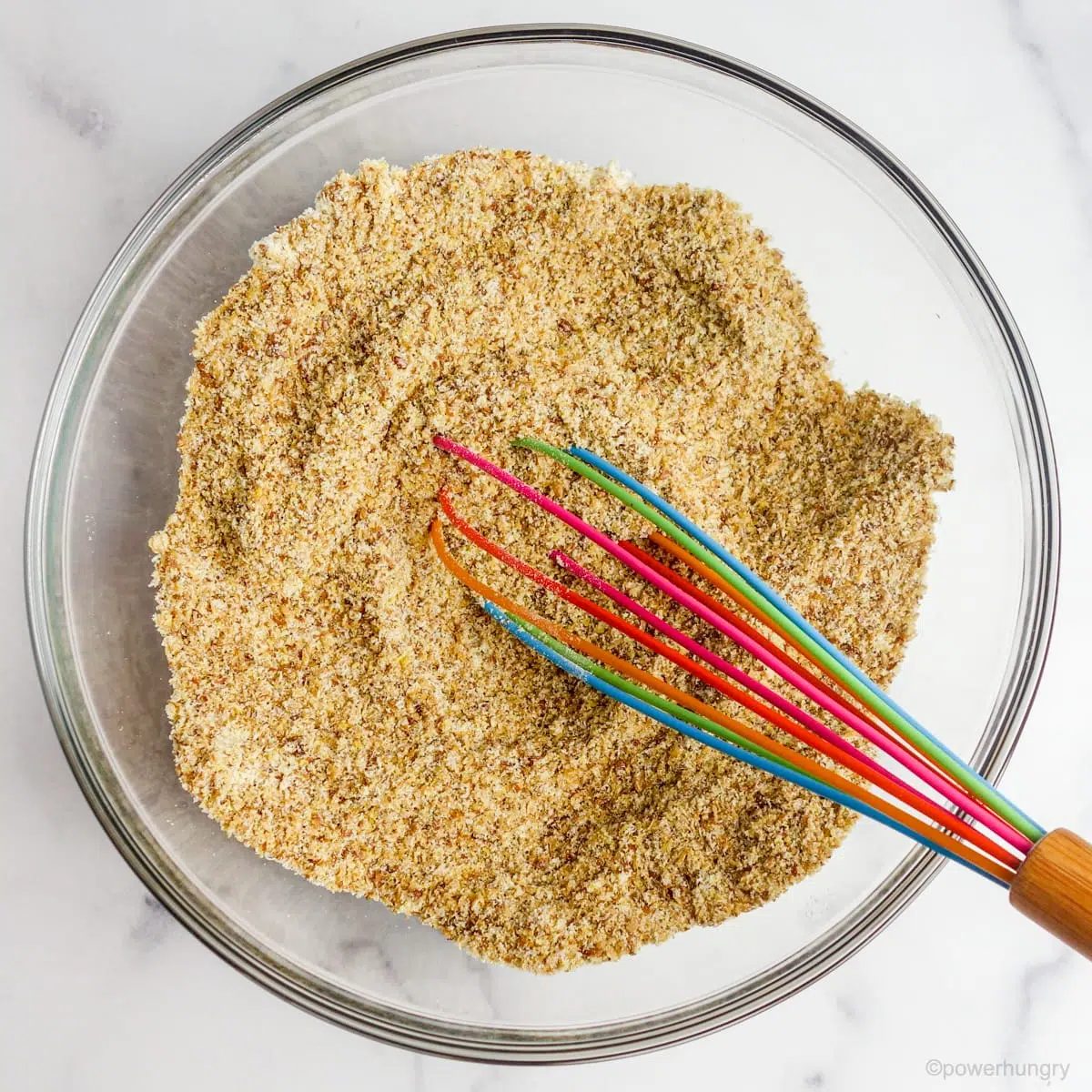 overhead shot of a glass bowl filled with the dry ingredients for coconut flour flax bread