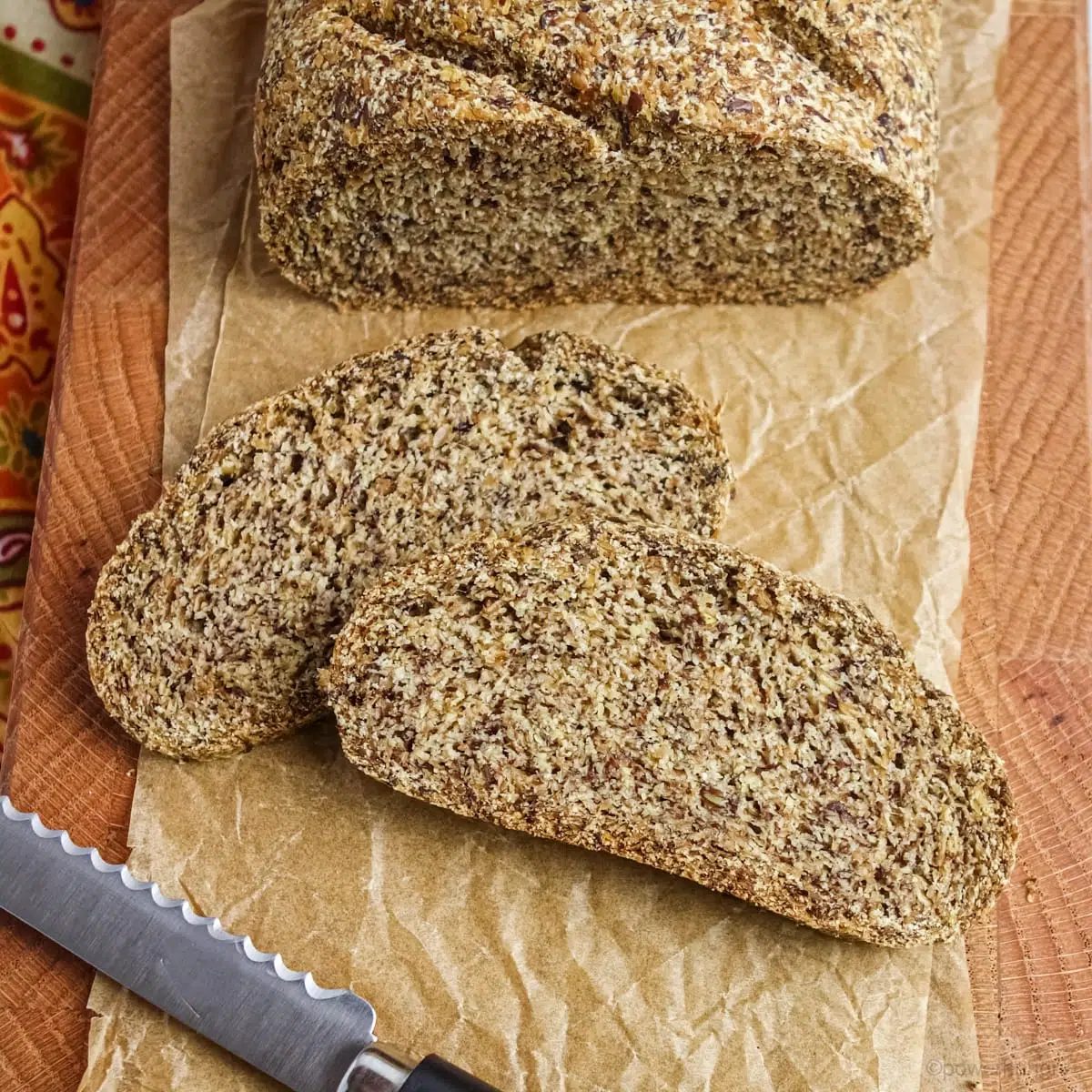 loaf of coconut flour flax bread on a wood cutting board, with several slices cut off