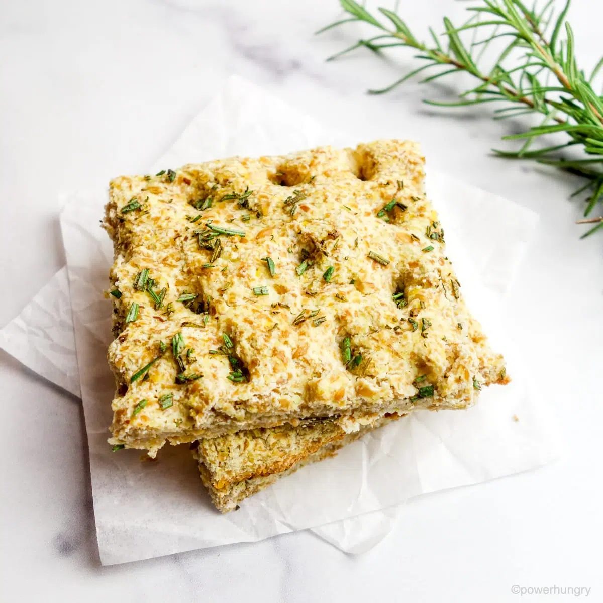 Two slices of coconut flour focaccia on white parchment paper