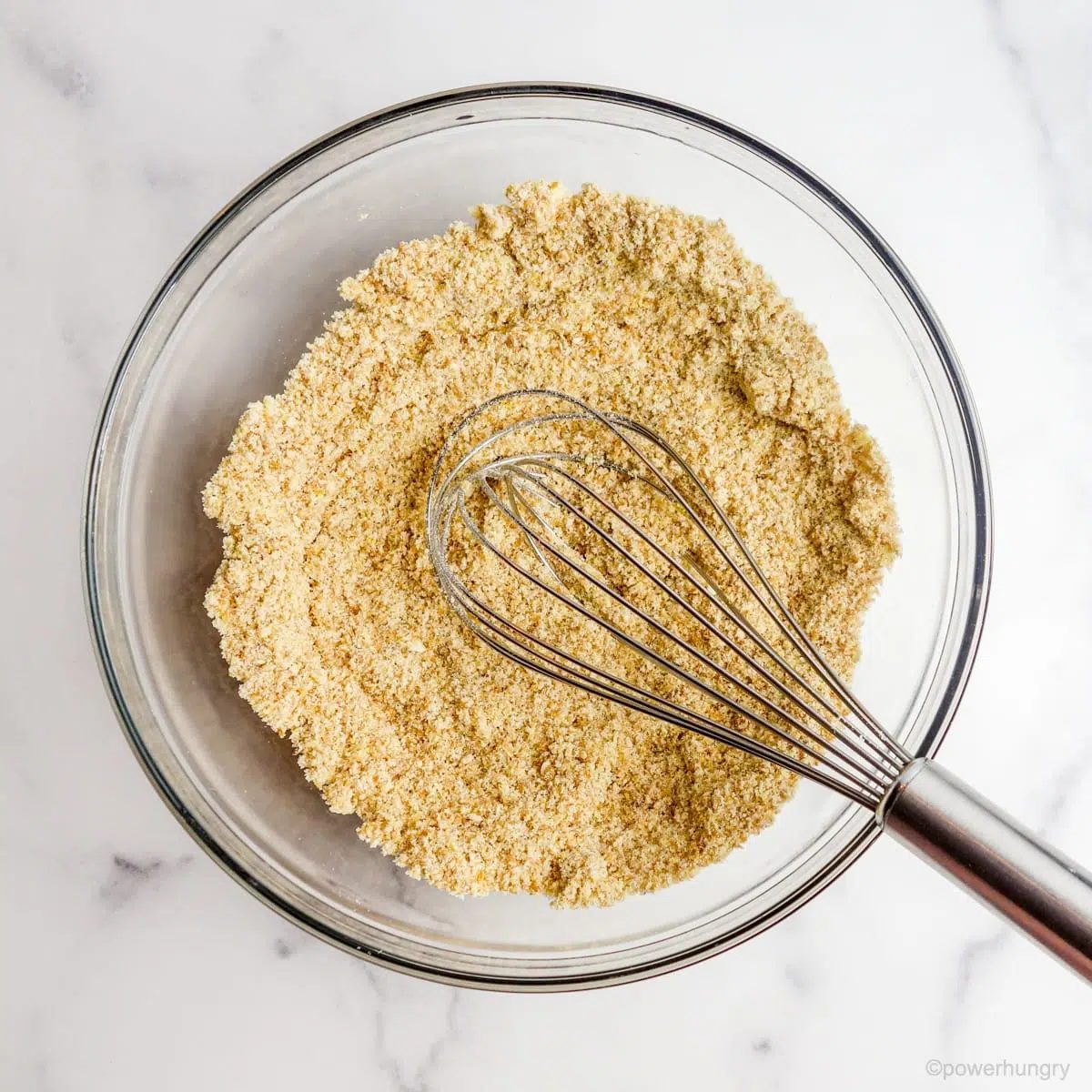 Overhead shot of glass bowl filled with ingredients for coconut flour flatbread