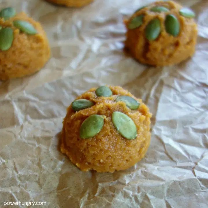 Scoops of coconut flour pumpkin cookie dough on a parchment paper lined baking sheet.