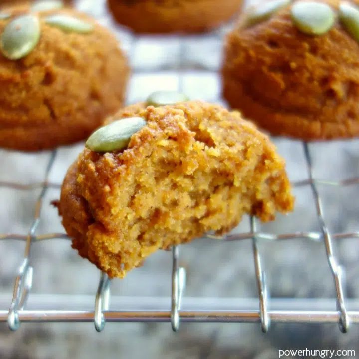coconut flour pumpkin cookie, with a bite taken out of it, on a wire cooling rack.
