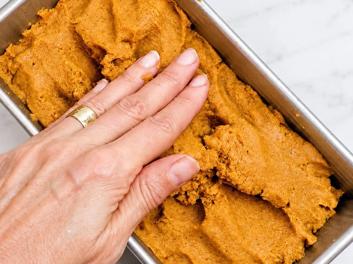 shaping the loaf of coconut flour pumpkin bread dough in a pan