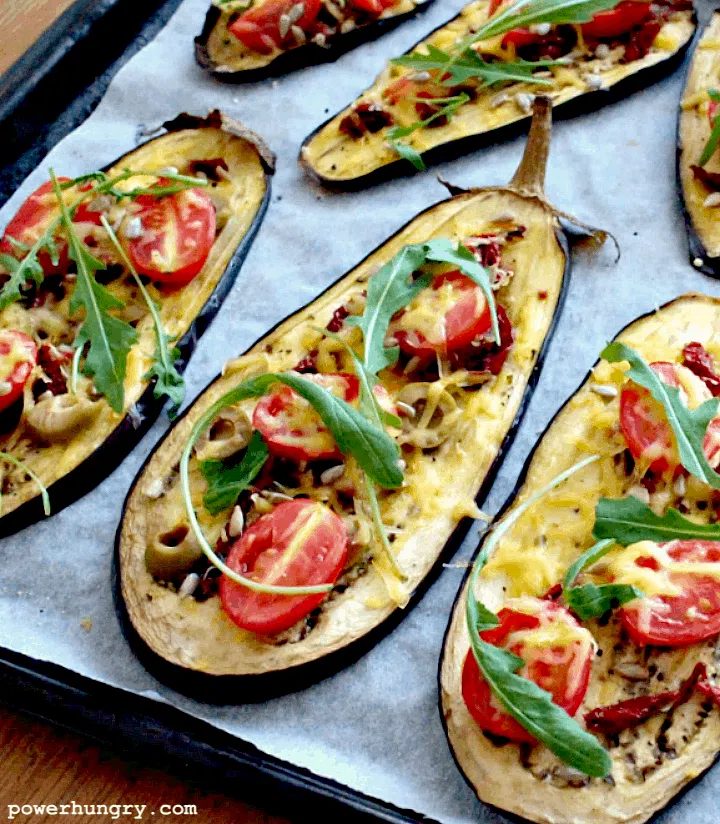 close-up of eggplant pizza slices topped with arugula and cherry tomatoes