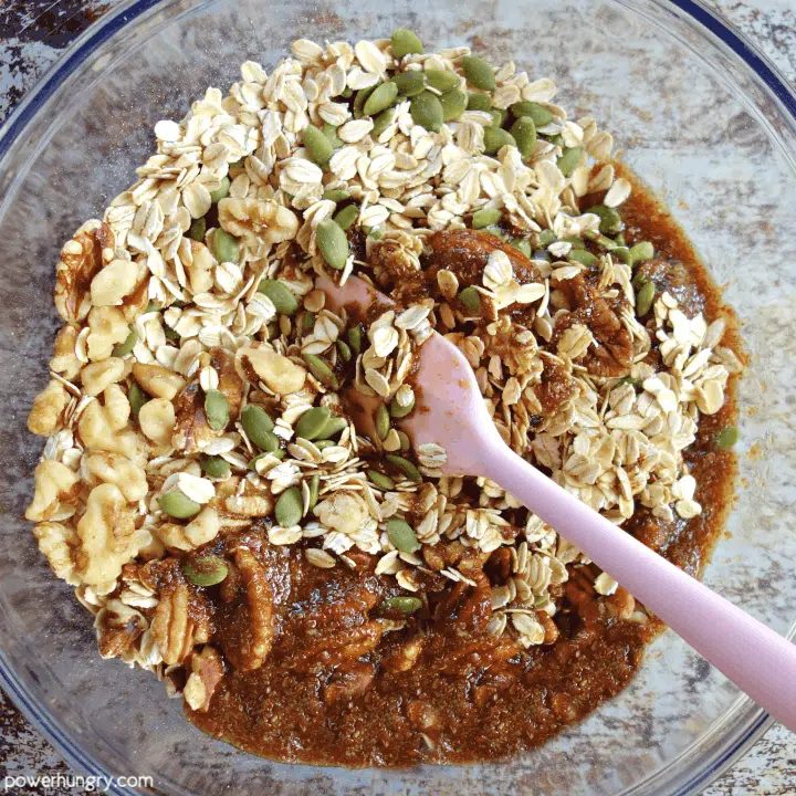 overhead shot of glass bowl with the ingredients for oil-free granola being mixed together