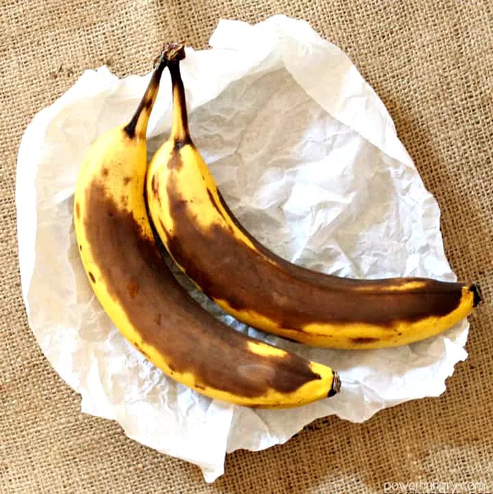 2 very ripe bananas on a piece of white parchment paper, atop a piece of burlap