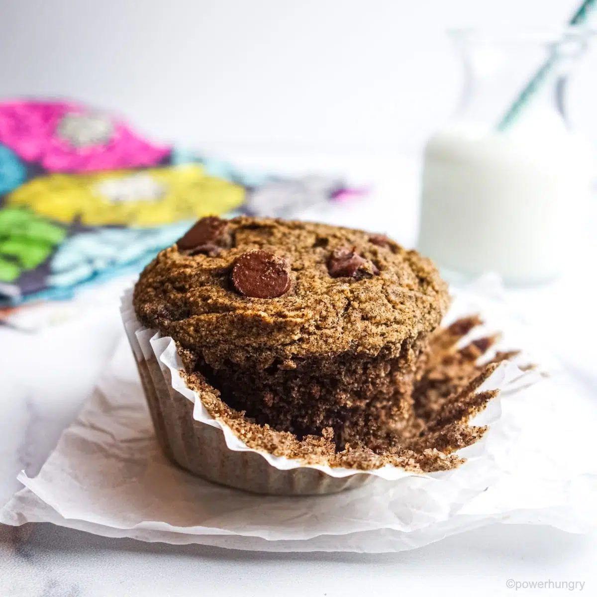 single buckwheat muffin with chocolate chips with the white paper liner partially removed
