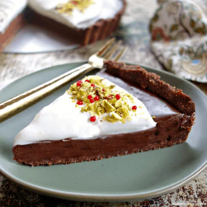 slice of vegan keto chocolate tart on a sage green dessert plate, a gold fork alongside