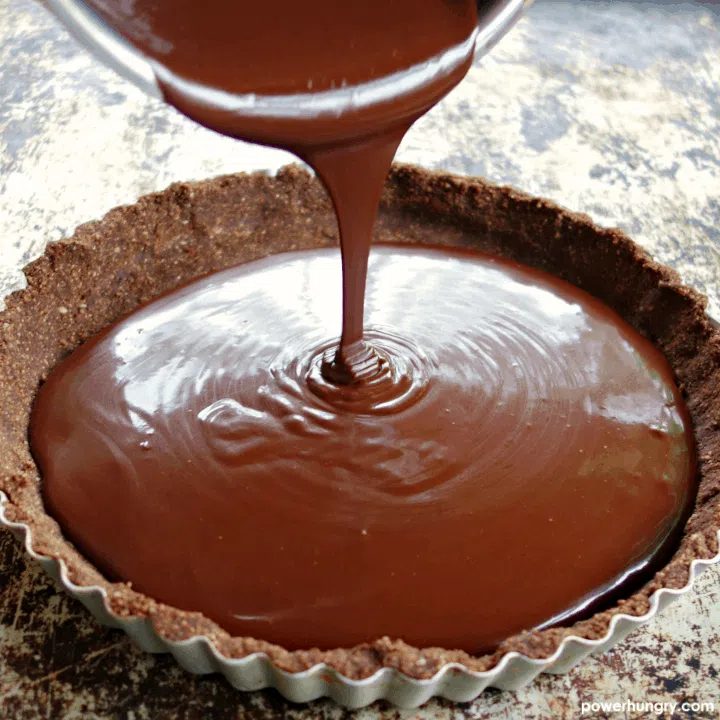 chocolate truffle filling being poured into a chocolate almond crust