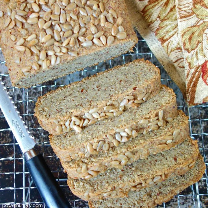 overhead sht of vegan keto sunflower seed bread , sliced, with a cutting knife and napkin alongside