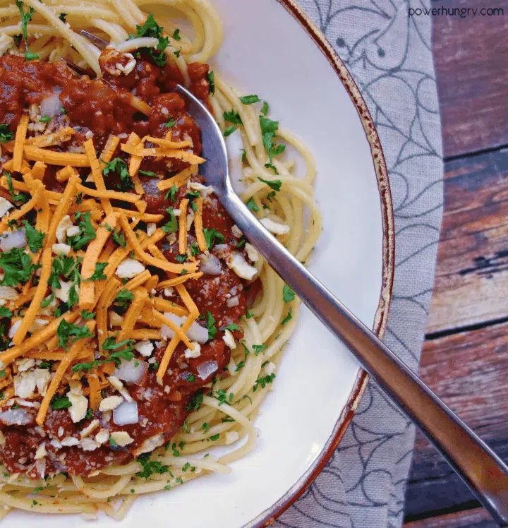 Up close of Vegan Lentil Cincinnati Chili in a white bowl on a tan napkin