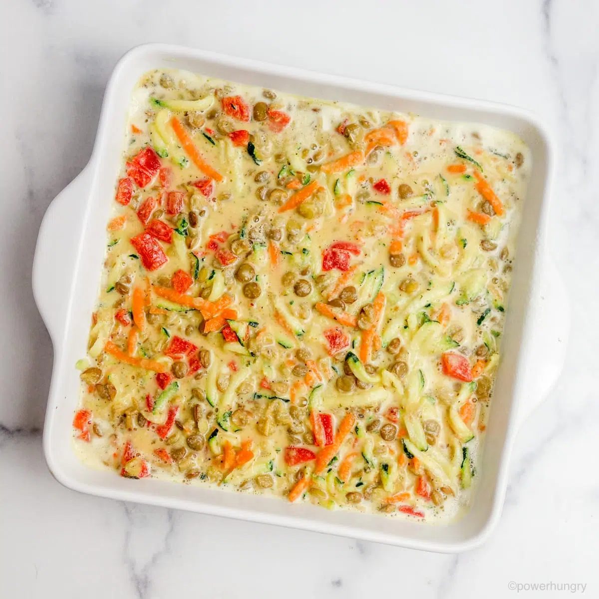 white square casserole dish filled with bowl filled with the batter and fillings for vegan lentil frittata bars
