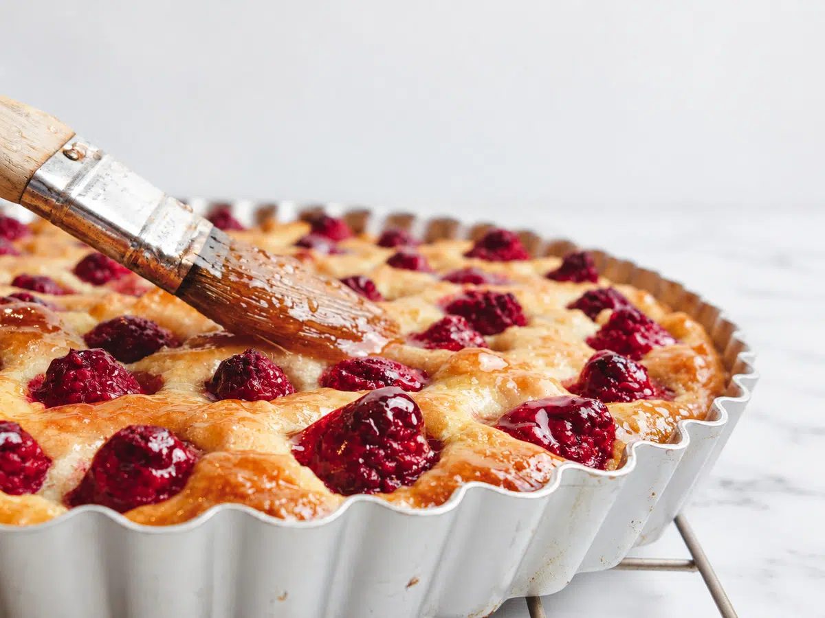 crustless frangipane tart with raspberries getting glaze