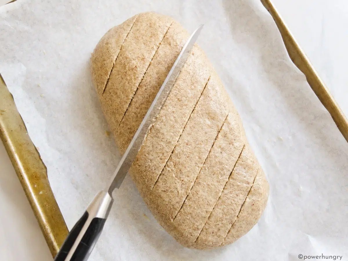 a knife slashing the top of vegan oat fiber bread loaf dough