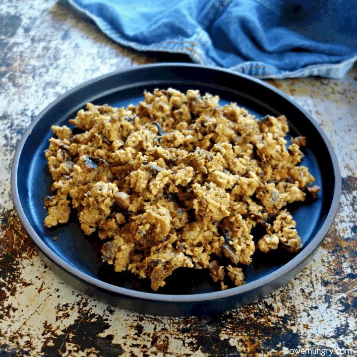 Vegan oat mushroom ground beef that has been sautéed, plated on a black plate
