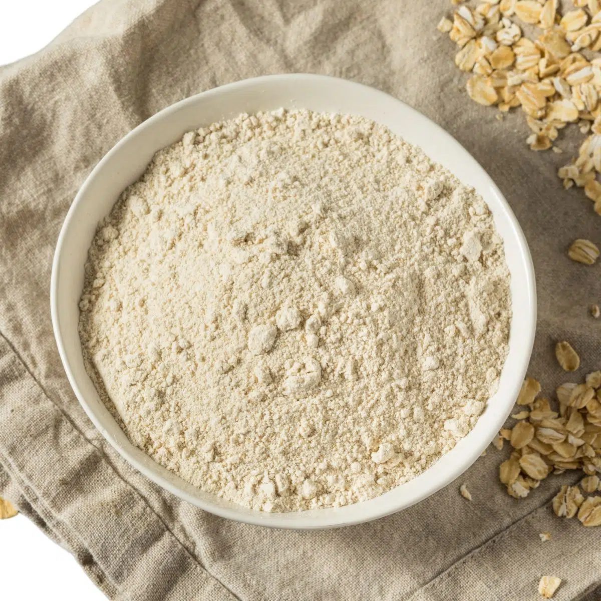 white bowl filled with oat flour on a tan napkin