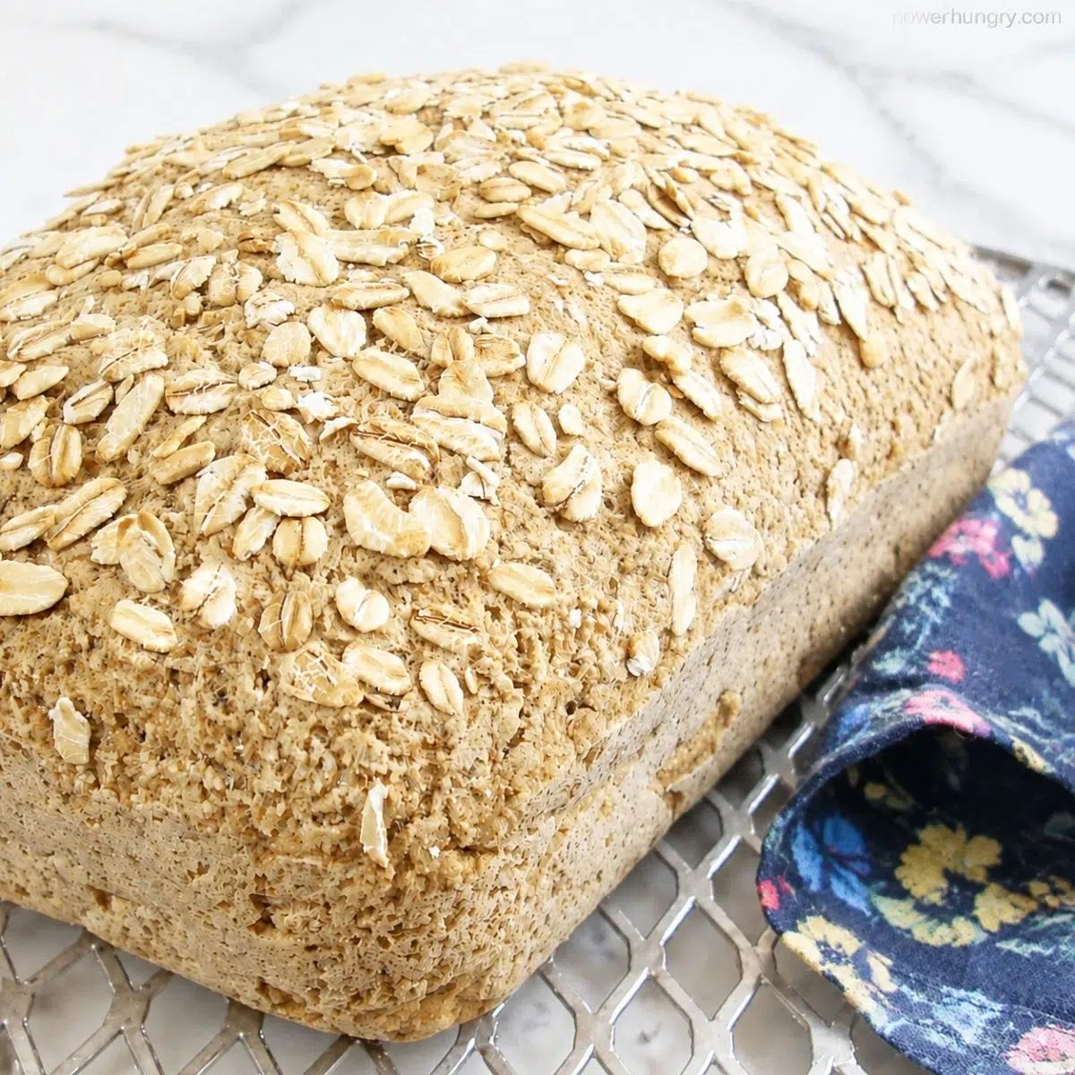baked loaf of vegan glutne-free oat flour sandwich bread on a cooling rack