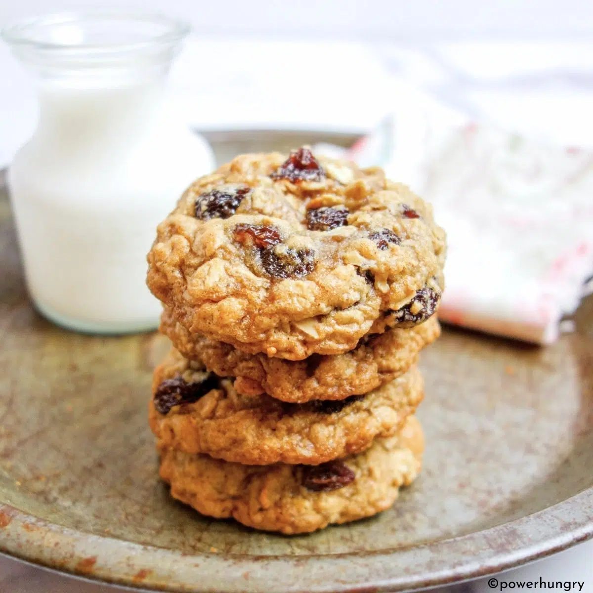 a stack of oatmeal raisin cookies in an antique pie plate