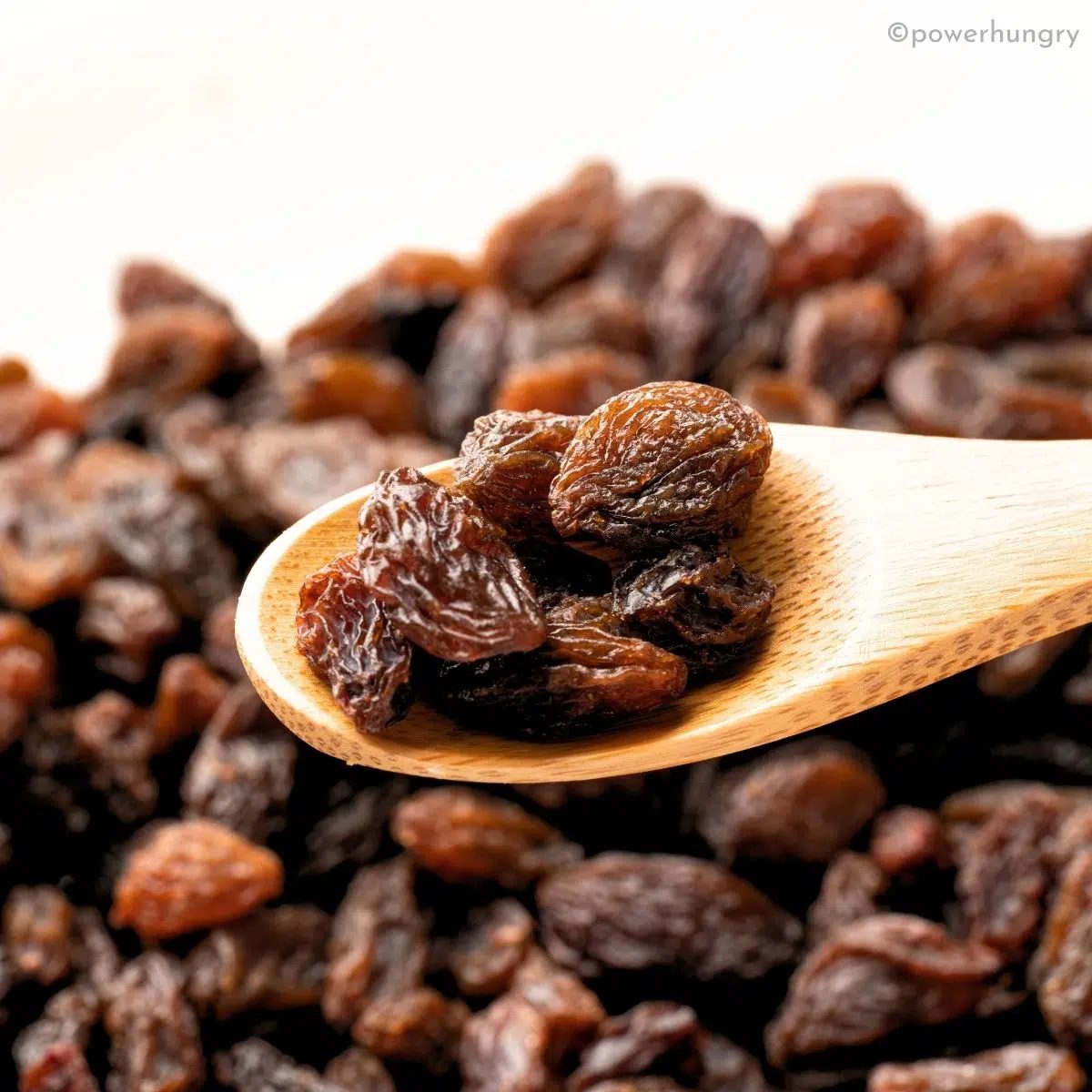 close up of raisins in a wooden spoon