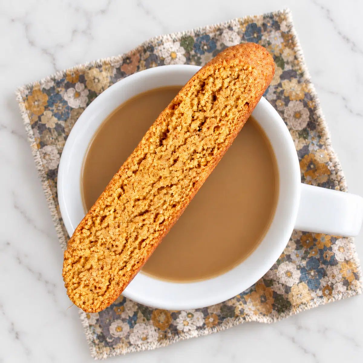 a single pumpkin almond flour biscotti over a cup of coffee
