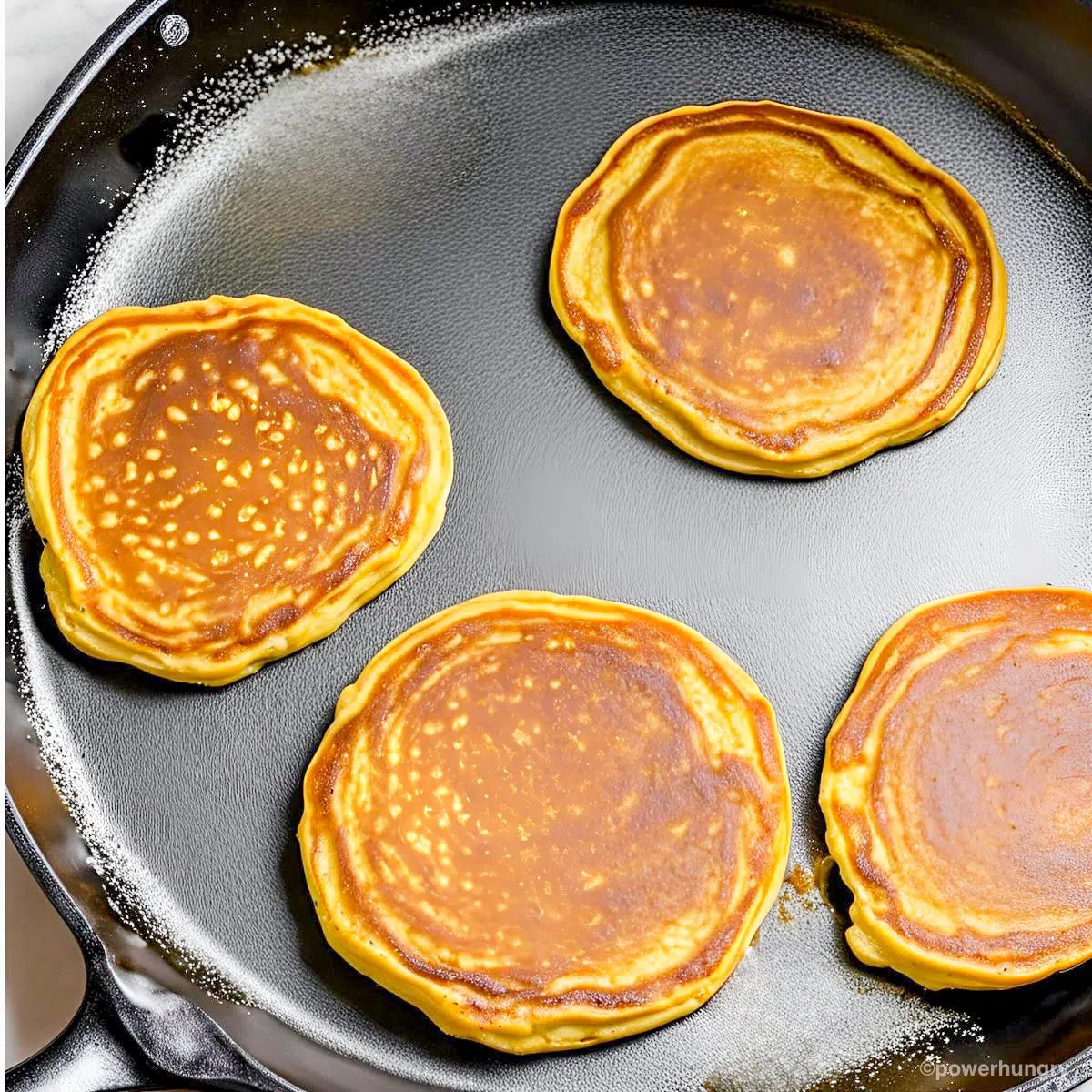 grain free pumpkin pancakes cooking in a skillet