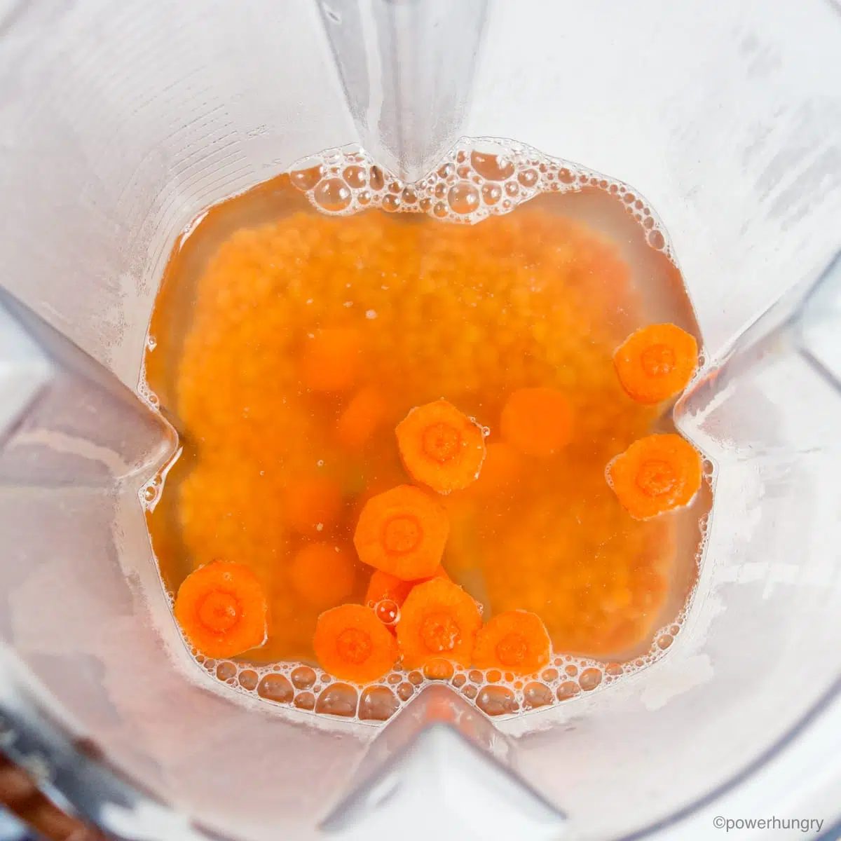 red lentils and carrots soaking in boiling water in a blender container