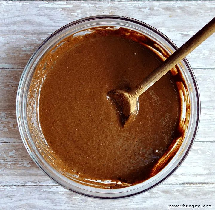 tigernut flour brownie batter in a glass bowl with a wooden spoon