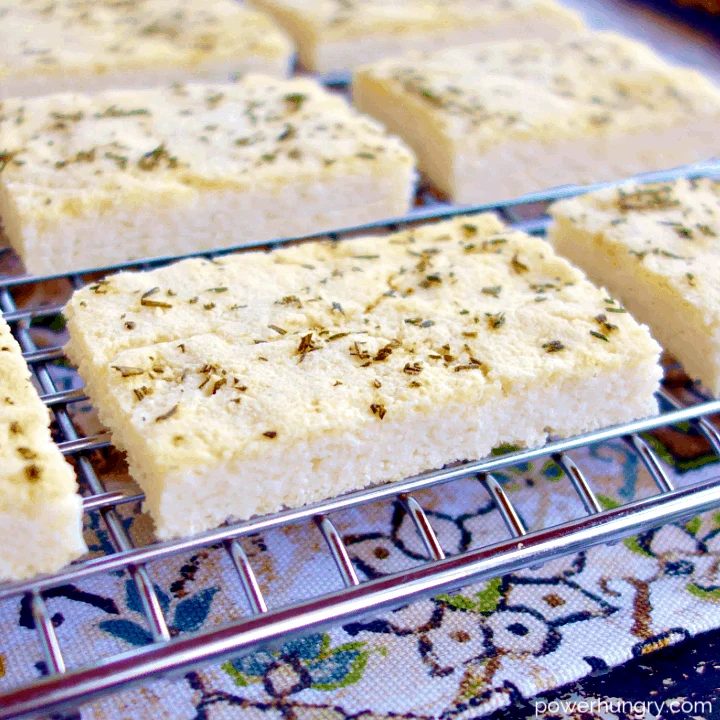 multiple pieces of white bean flatbread on a silver cooling rack