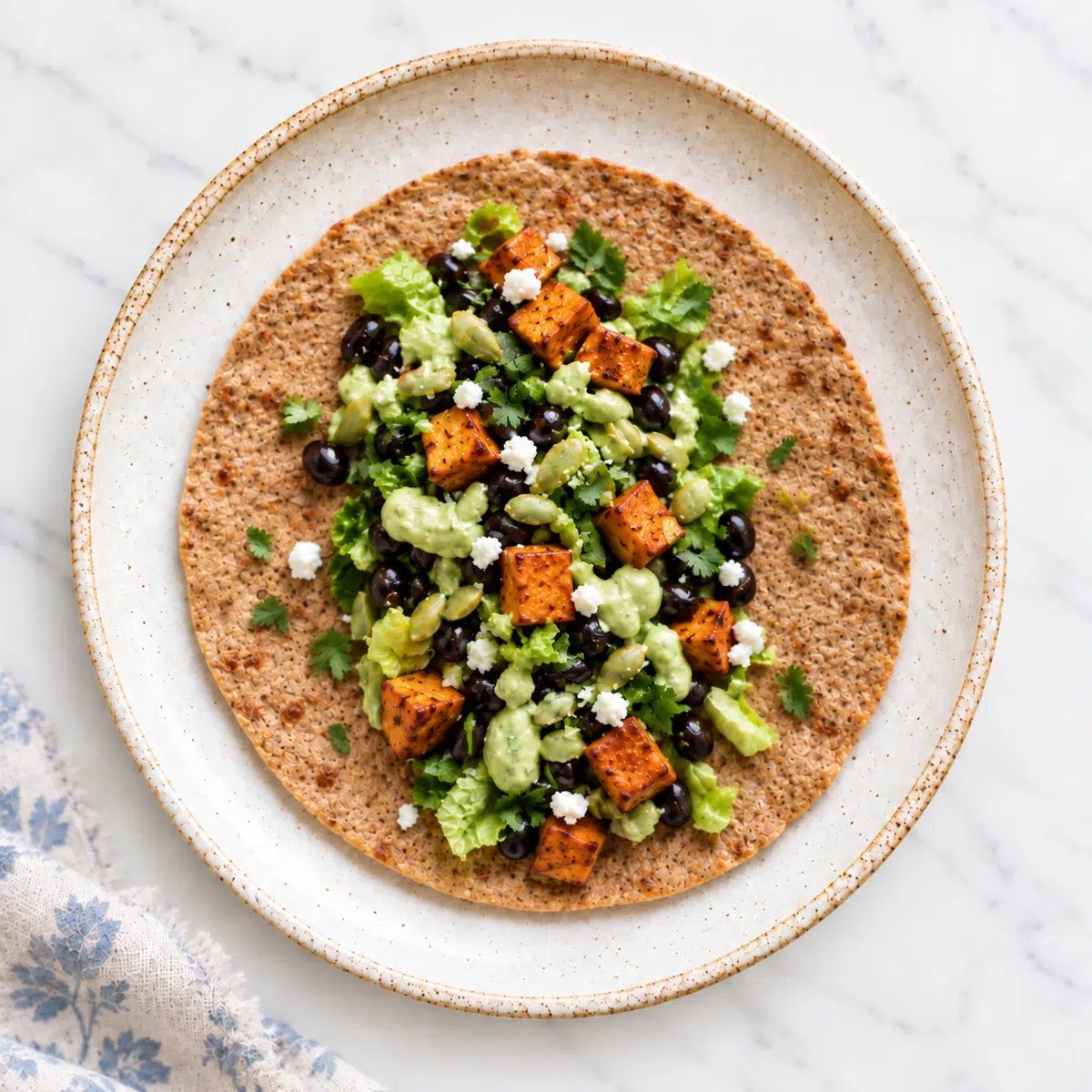 overhead view of the flaxseed tortilla topped with black beans and guacamole sauce with sweet potatoes