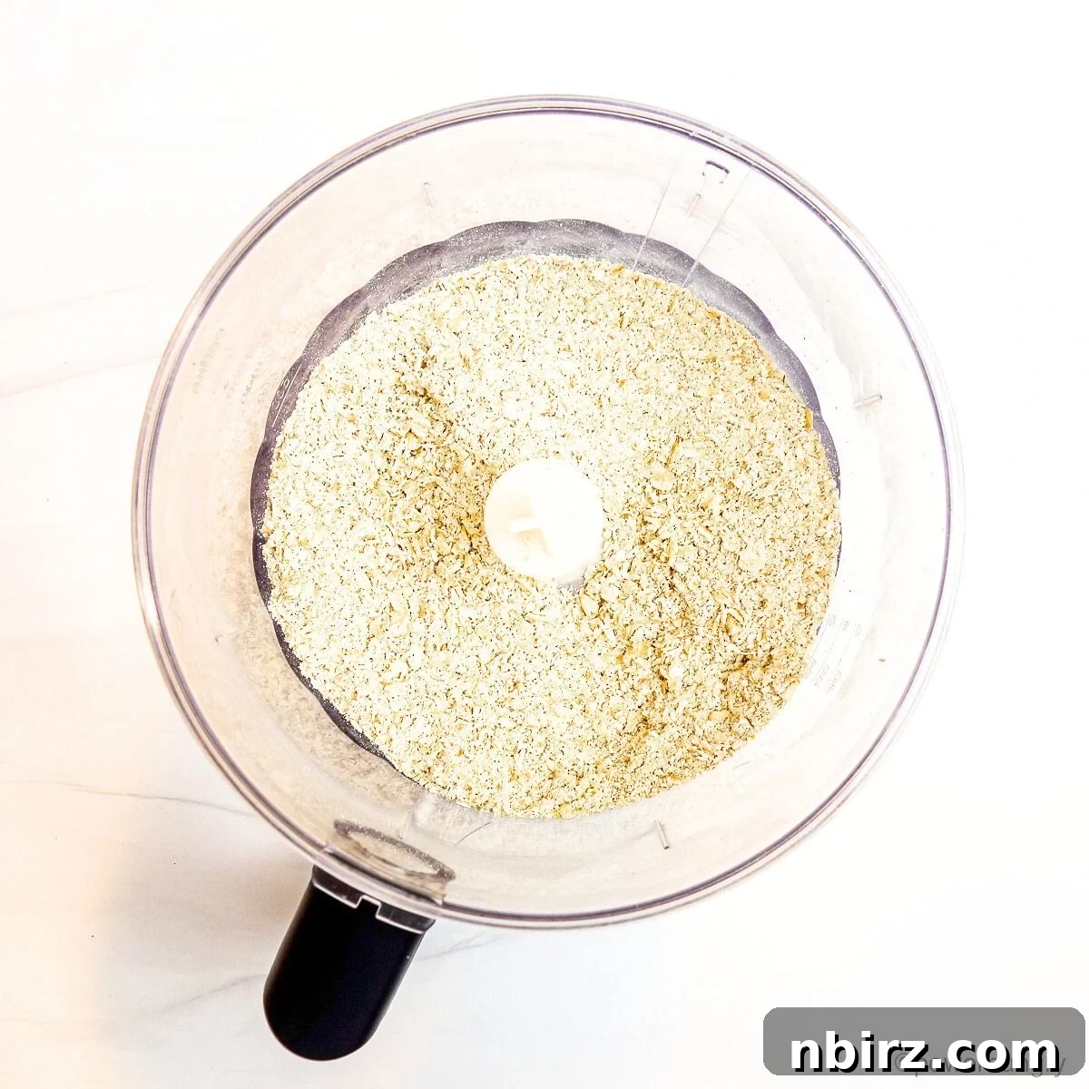 Wholesome Scottish Vegan Gluten Free Oatcakes 4 Close-up shot of ground oats in a food processor bowl, showing the transformation from whole oats to a finer texture