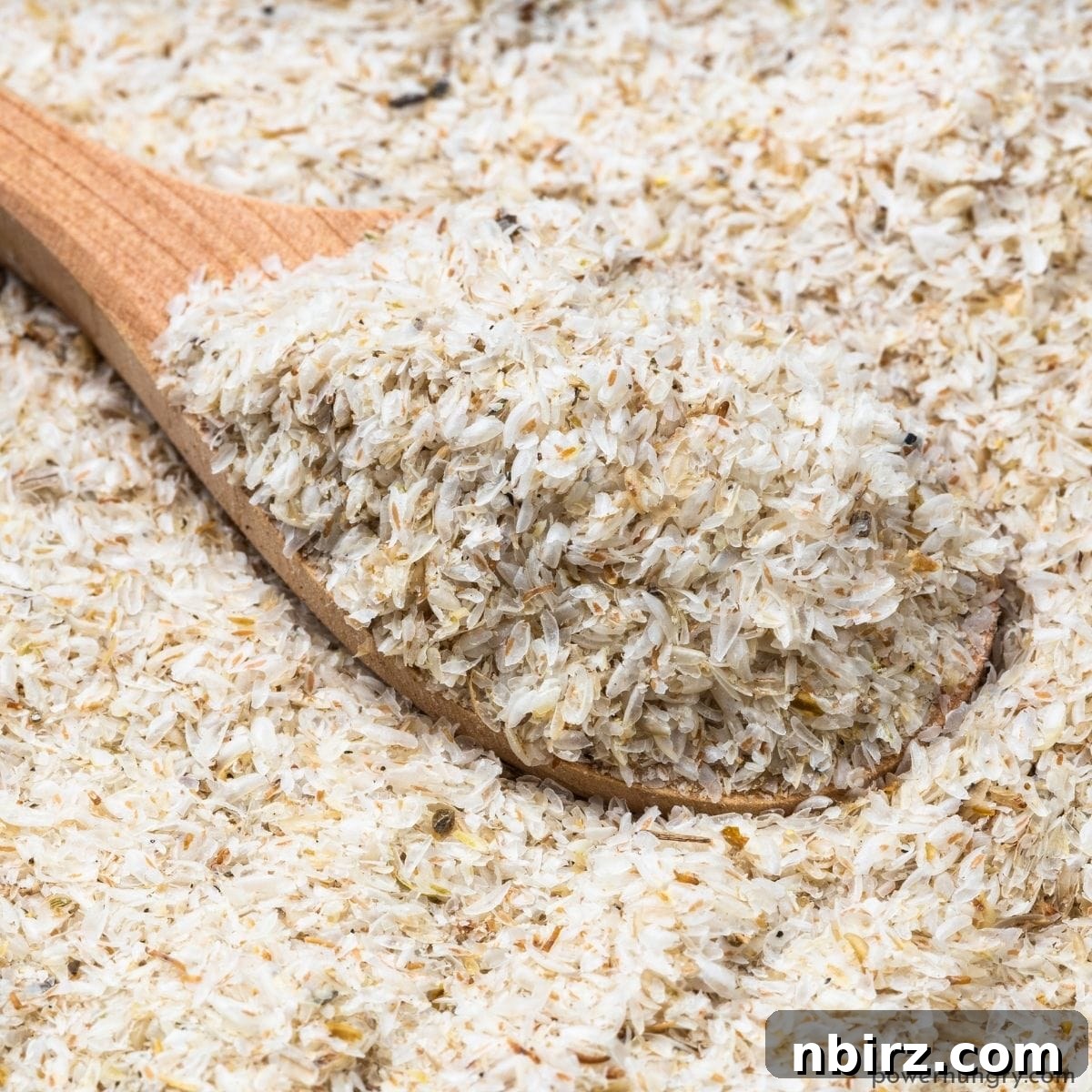 Wooden spoon in a wooden bowl scooping up some whole psyllium husks, showing their texture.