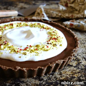 A beautifully presented vegan keto chocolate truffle tart, a slice removed to show its rich, dense filling.