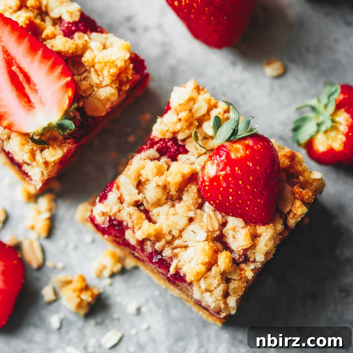 Wholesome Gluten-Free Vegan Strawberry Oat Bars 2 Healthy strawberry oatmeal bars arranged on a minimalist grey background, showcasing their inviting texture and fresh fruit topping