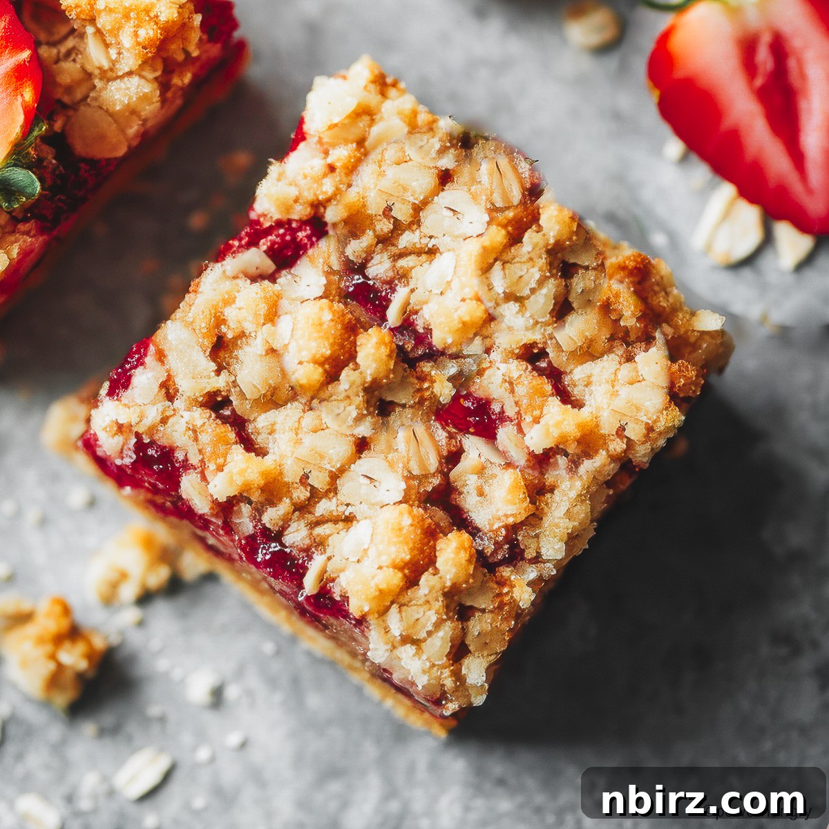 Wholesome Gluten-Free Vegan Strawberry Oat Bars 4 A single healthy strawberry oatmeal bar placed on a grey surface, ready to be enjoyed